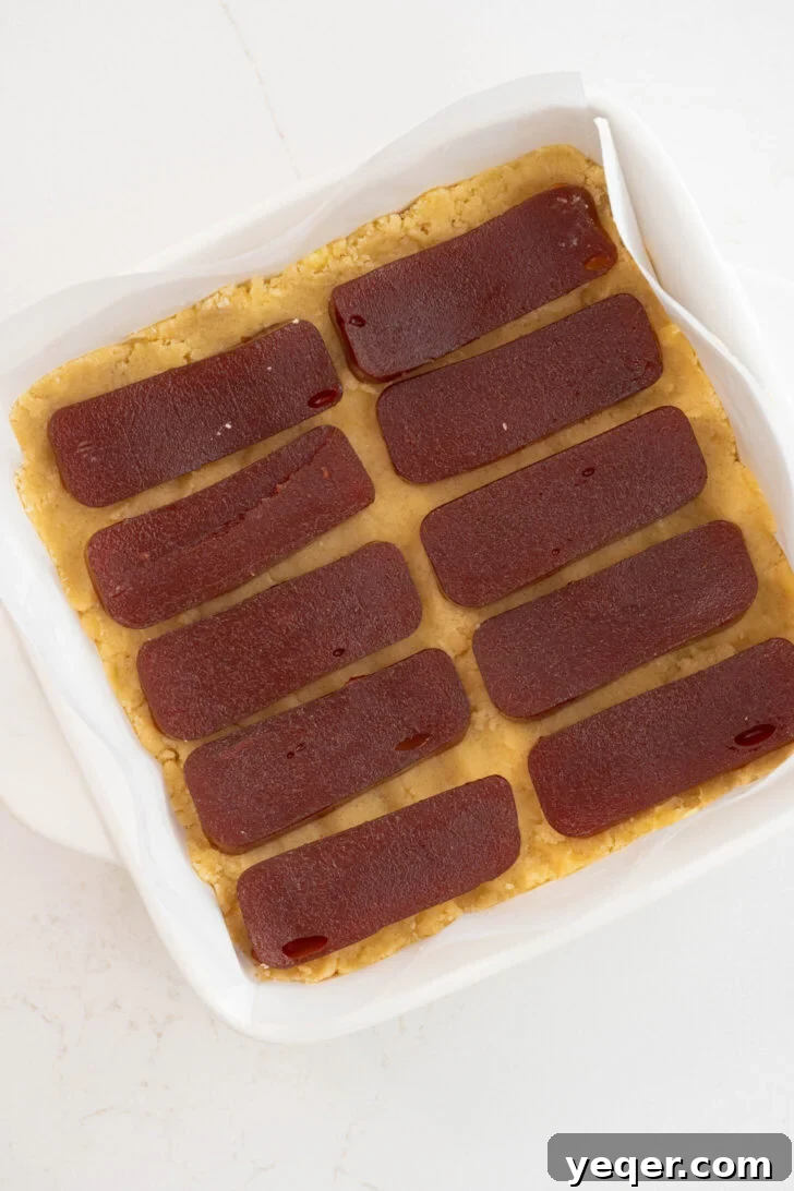 Golden Guava Crumble Bars 6 Guava bars being assembled in a baking dish, with the dough pressed and guava paste layered.