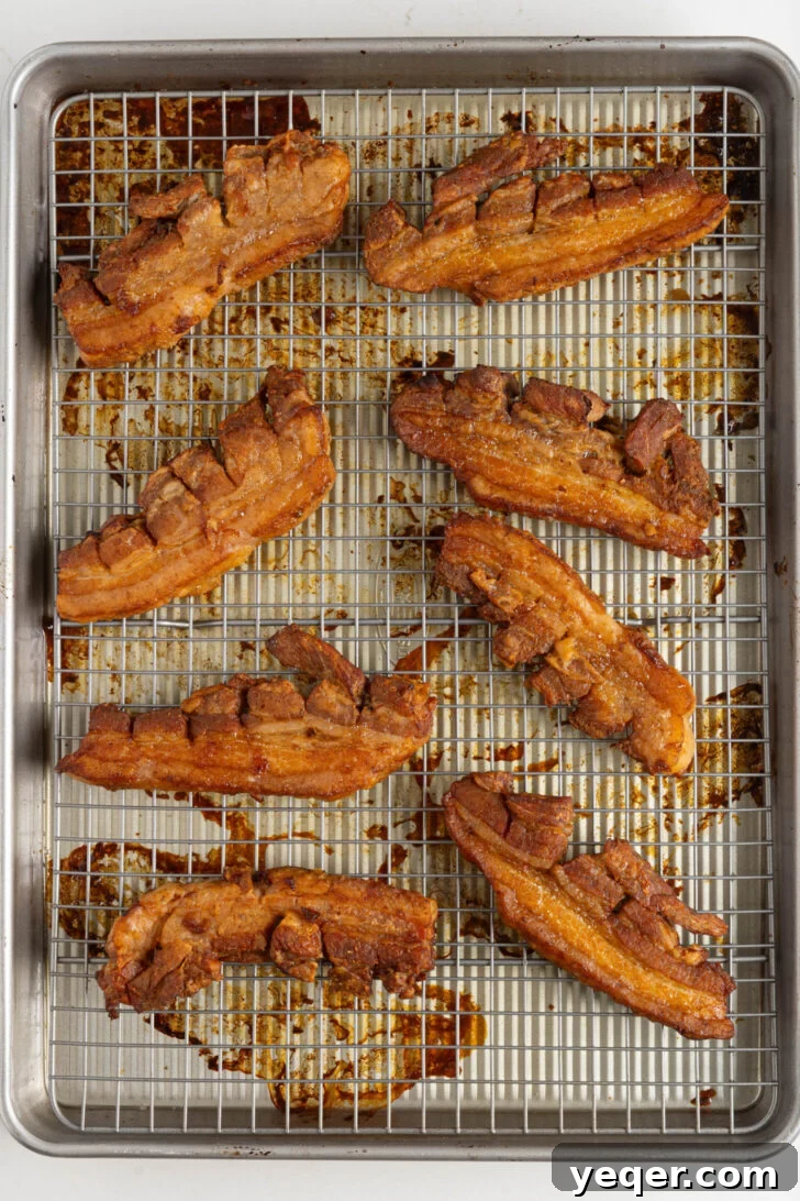 Crackling Oven-Roasted Pork Belly 6 Golden-brown, crispy chicharrones on a baking rack over a sheet pan.