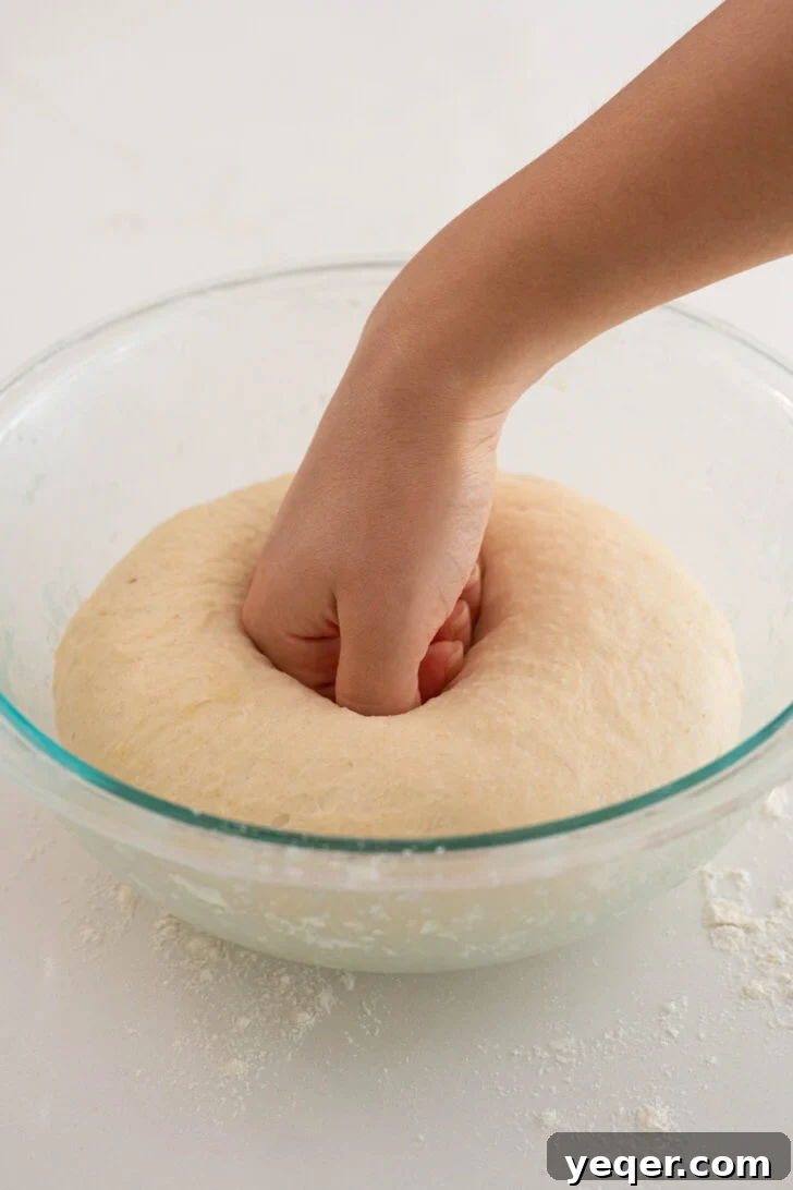 Pan Sobao Puerto Rican Soft Sweet Bread 5 A hand punching down soft Pan Sobao dough in a bowl.