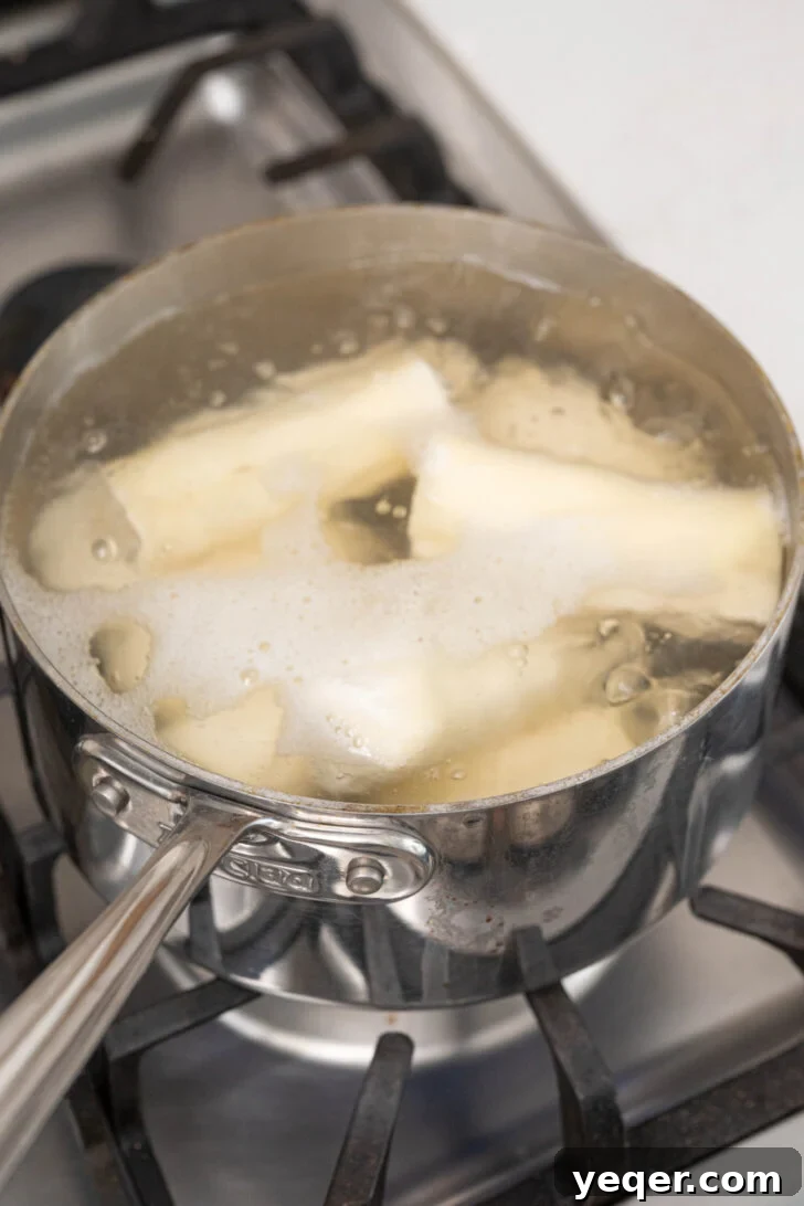 Zesty Garlic Steamed Yuca 4 Yuca pieces boiling in a pot of salted water until tender.