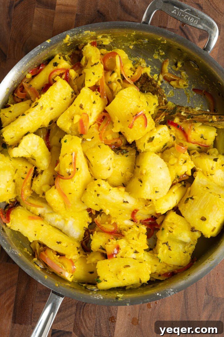 Zesty Garlic Steamed Yuca 7 Cooked yuca pieces being tossed with the vibrant garlic mojo sauce in a pan.