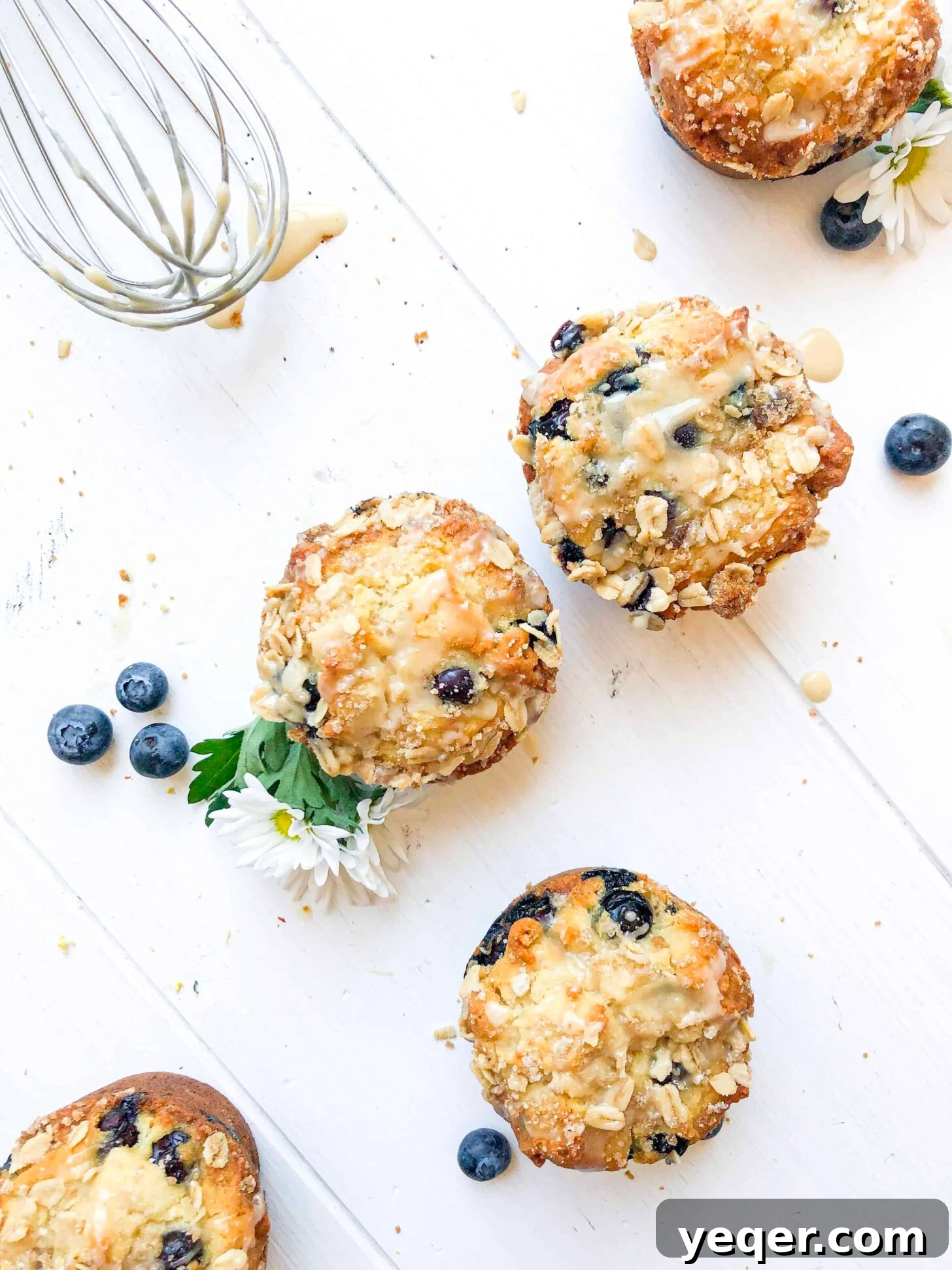 Irresistible Vegan Gluten-Free Blueberry Oat Muffins 2 Vegan blueberry muffins on a white table with a whisk