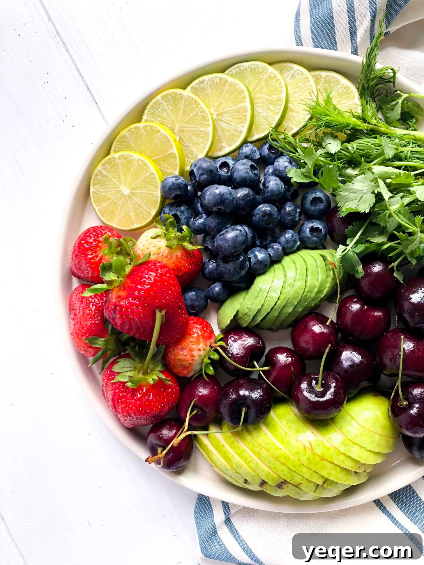 Botanical Bites Board 4 A vibrant assortment of freshly cut fruit slices, including bright green limes, arranged artfully on a white plate, ready for a charcuterie board.
