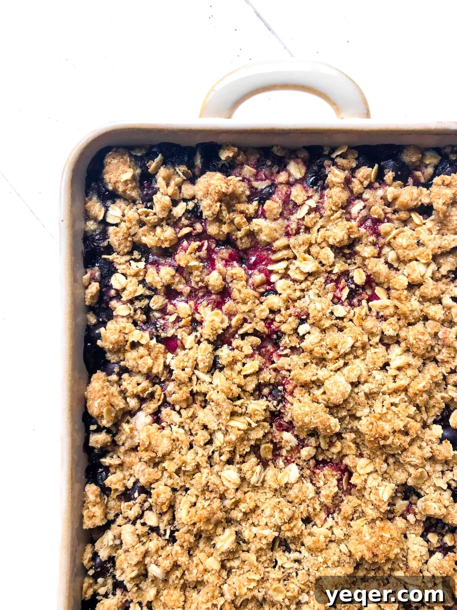 Heavenly Gluten Free Berry Crumble 2 A golden-brown gluten-free berry crisp in a rectangular baking pan, showcasing the vibrant berry filling bubbling beneath the crispy oat topping, ready to be served.