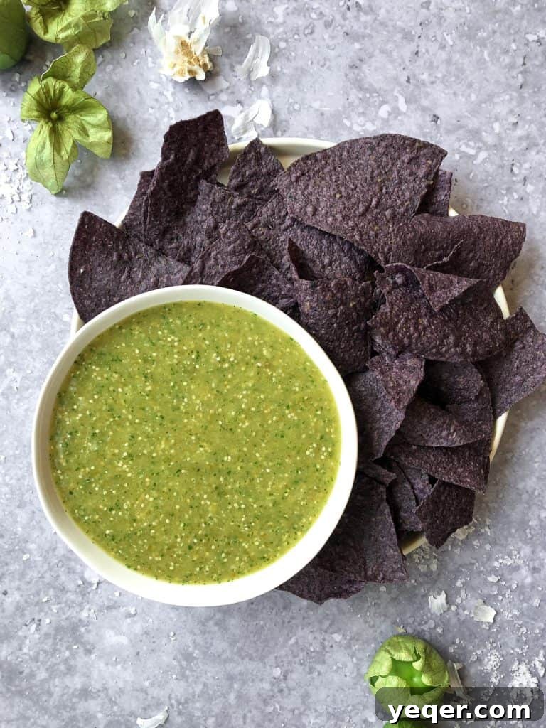 Smoky Tomatillo Salsa 2 A beautifully presented bowl of freshly made roasted salsa verde, accompanied by crispy blue corn chips, inviting you to dip in.