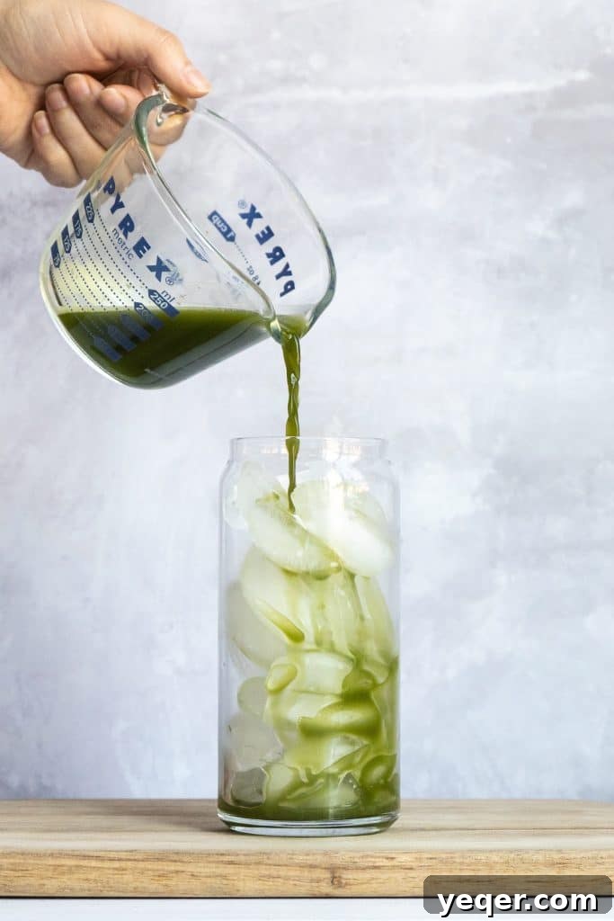 Effortless 4-Ingredient Matcha Lattes, Whisk-Free 3 An inviting iced matcha latte in a clear glass, showcasing its distinct green and white layers.
