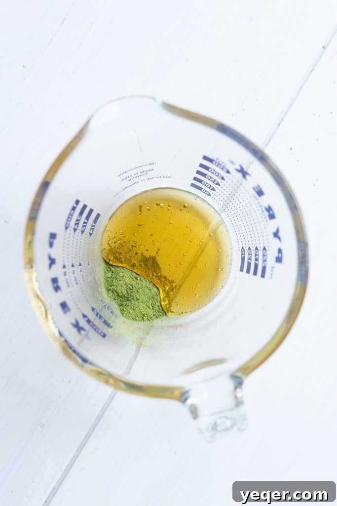 Effortless 4-Ingredient Matcha Lattes, Whisk-Free 4 A small bowl containing a thick, dark green matcha and honey paste, ready for water.