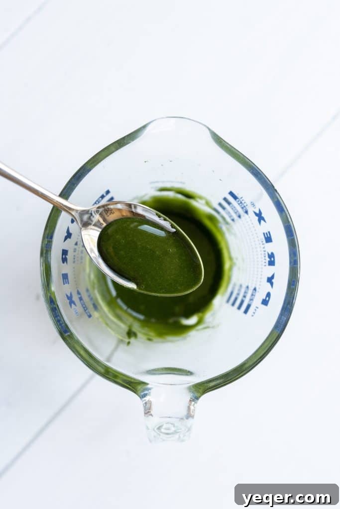 Effortless 4-Ingredient Matcha Lattes, Whisk-Free 5 A close-up shot of an iced matcha latte with visible ice cubes and distinct layers.