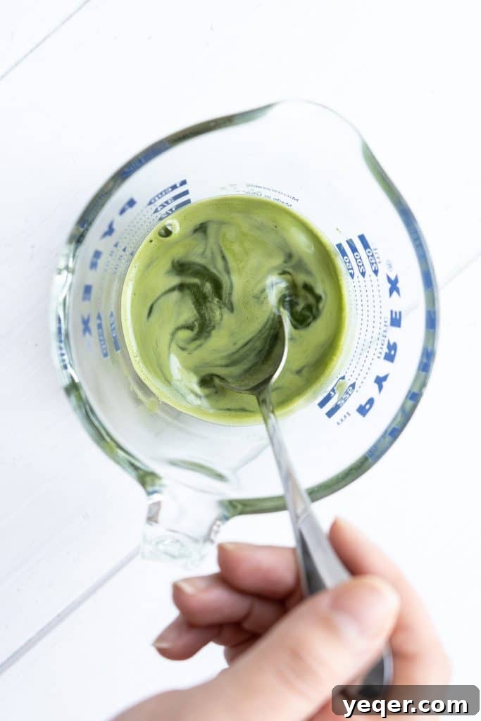 Effortless 4-Ingredient Matcha Lattes, Whisk-Free 6 A small, elegant bowl filled with bright green matcha powder, ready for preparation.
