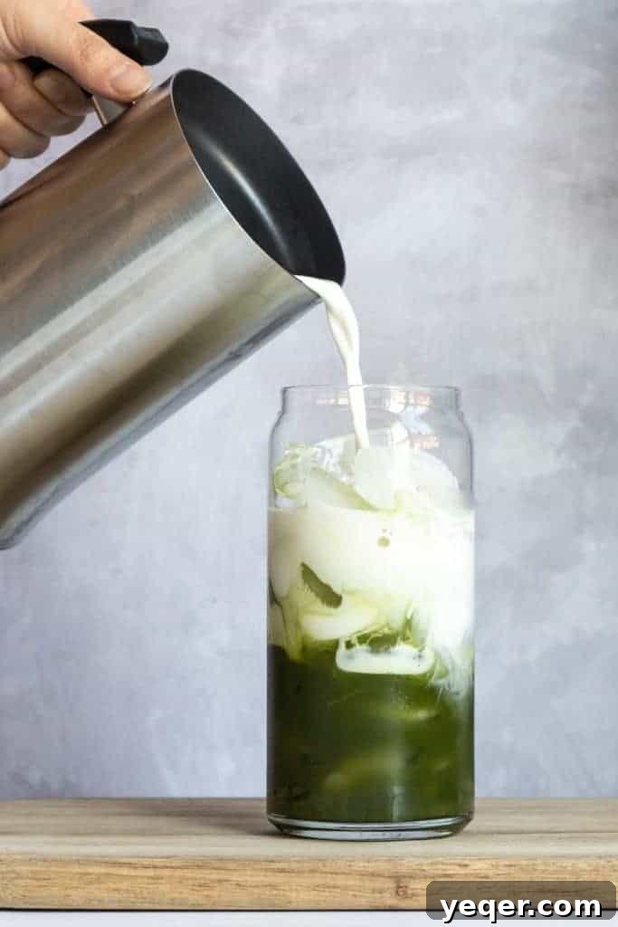 Effortless 4-Ingredient Matcha Lattes, Whisk-Free 7 A hand holding an iced matcha latte, with a gentle focus on the vibrant green drink.