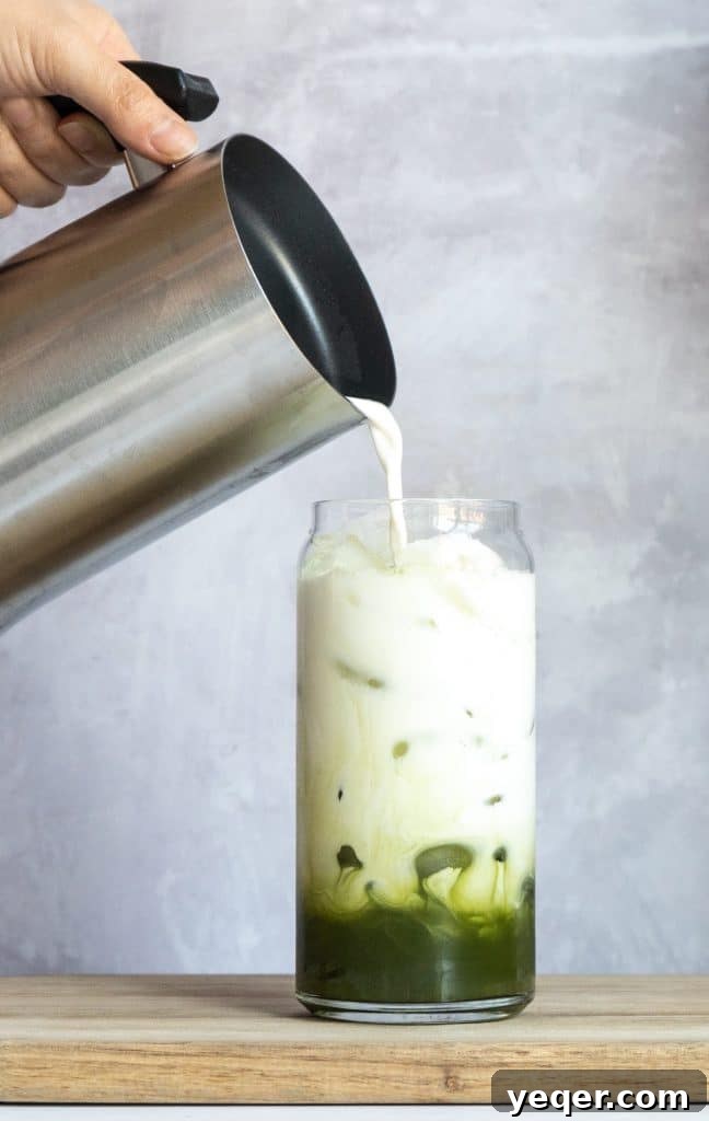 Effortless 4-Ingredient Matcha Lattes, Whisk-Free 8 A beautifully layered iced matcha latte with a straw, ready to be enjoyed.