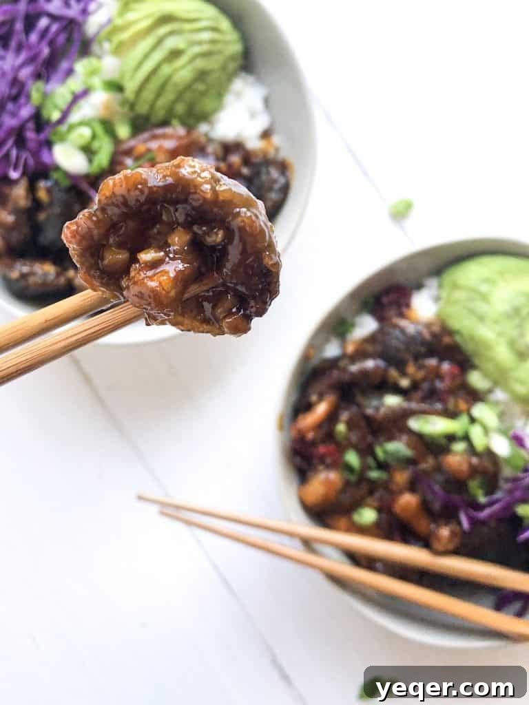 Two servings of Mongolian Shiitake Mushroom Bowls, garnished with fresh greens and sesame seeds, invitingly presented on a table.