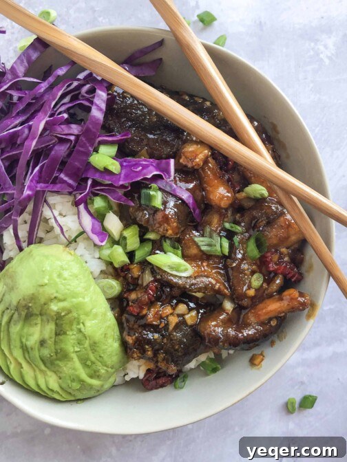 A bowl of Mongolian Shiitake Mushrooms with rice and fresh garnishes.