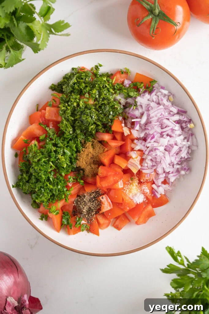 Vibrant Moroccan Tomato Salad 7 A bowl filled with freshly diced tomatoes, minced herbs, and red onion, ready to be combined with dressing for the Moroccan tomato salad.
