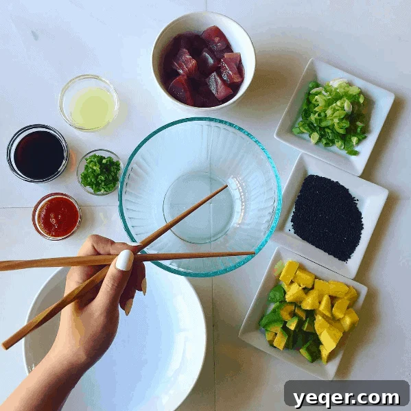 Tropical Avocado Mango Poke Bowls 2 Freshly sliced ahi tuna, vibrant mango, and creamy avocado, meticulously arranged with other ingredients for a delicious Hawaiian-inspired poke bowl, ready for marinating.
