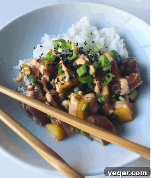Tropical Avocado Mango Poke Bowls 3 A vibrant and colorful Hawaiian-inspired poke bowl generously topped with fresh mango and avocado slices, ready to be enjoyed.