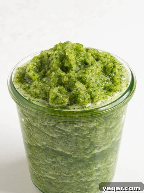 A jar of homemade sofrito, displaying its vibrant green color.