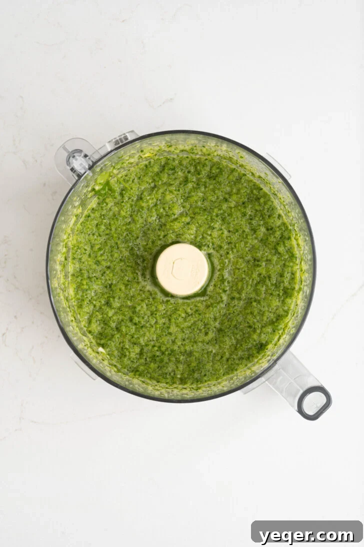 Vibrant Homemade Puerto Rican Sofrito 7 A food processor containing freshly blended sofrito, exhibiting a uniform green paste.