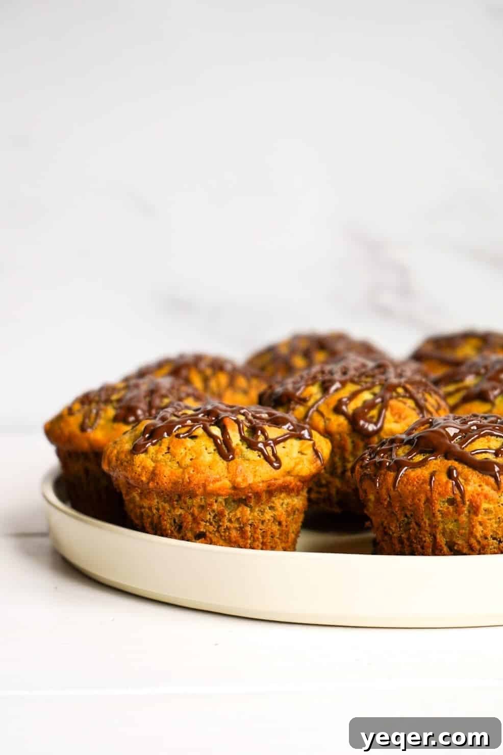 Decadent Chocolate-Swirled Banana Oat Muffins 7 Banana oat muffins arranged neatly on a plate, ready to be served.
