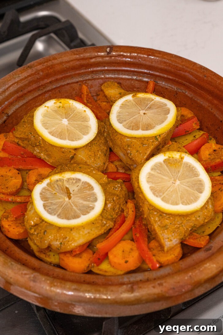 Moroccan Fish and Potato Tagine 6 A pot of Moroccan fish stew with white fish fillets, lemon slices, and a rich, simmering sauce.