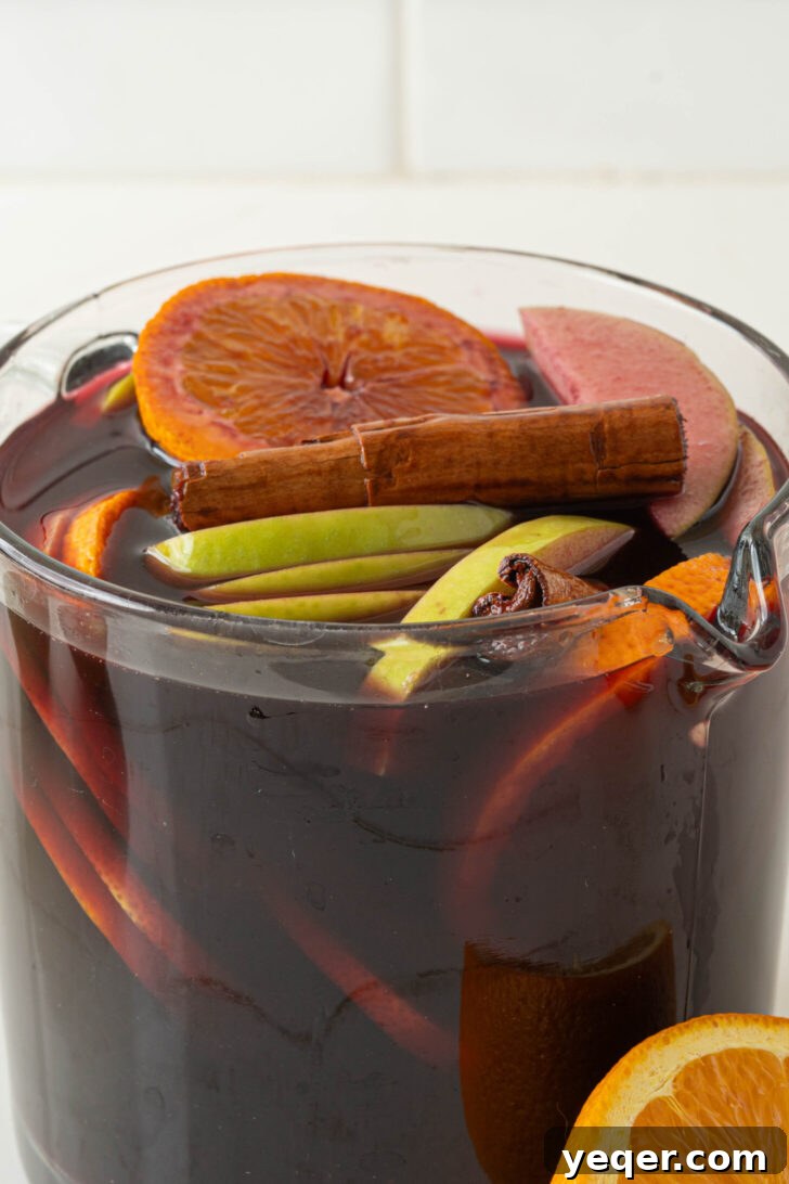 Authentic Spanish Red Sangria: Pitcher Perfect for Six 4 Pouring red wine into a pitcher with fruit, sugar, and cinnamon.