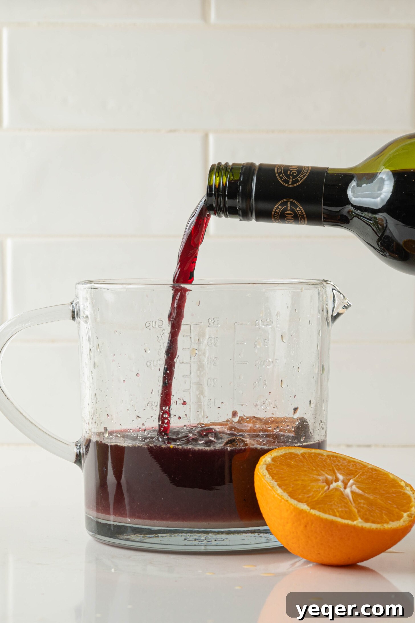 Authentic Spanish Red Sangria: Pitcher Perfect for Six 7 Red wine being poured into a pitcher full of fruit for sangria.